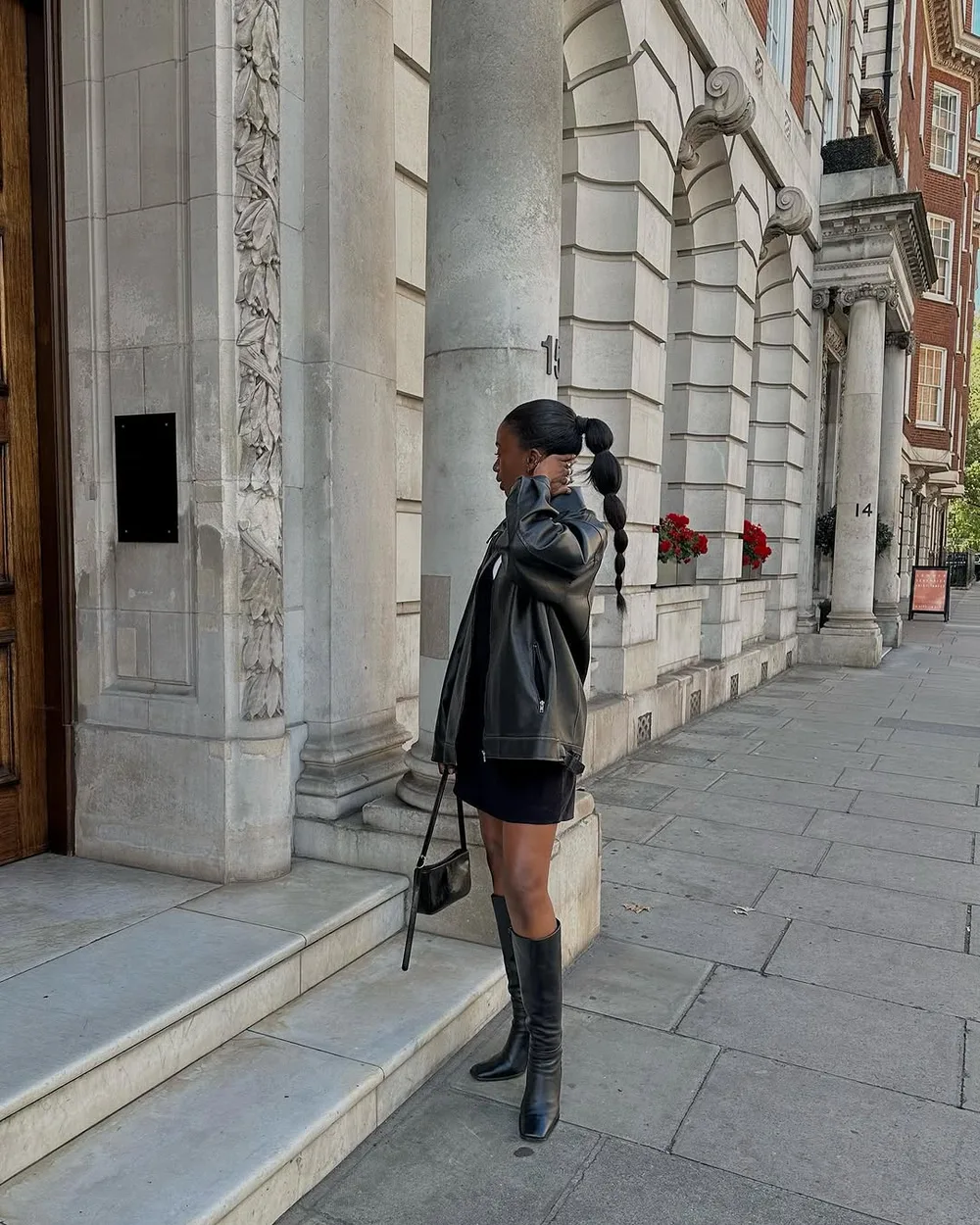 Mini robe noire portée sur un col roulé avec des bottes hautes
