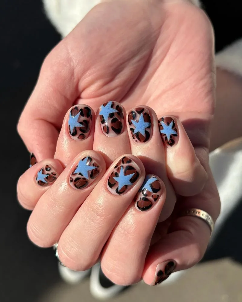 Nail art léopard avec étoiles bleues sur fond laiteux