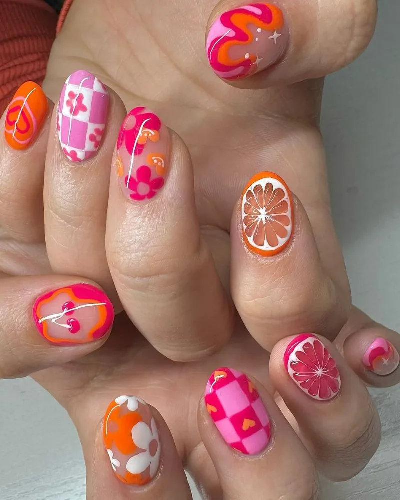 Nail art rose et orange avec motifs ludiques et cœurs sur ongles courts d'été