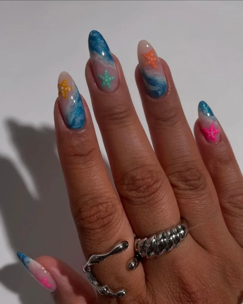 Ongles amande avec étoiles de mer colorées et vagues pailletées, nail art plage