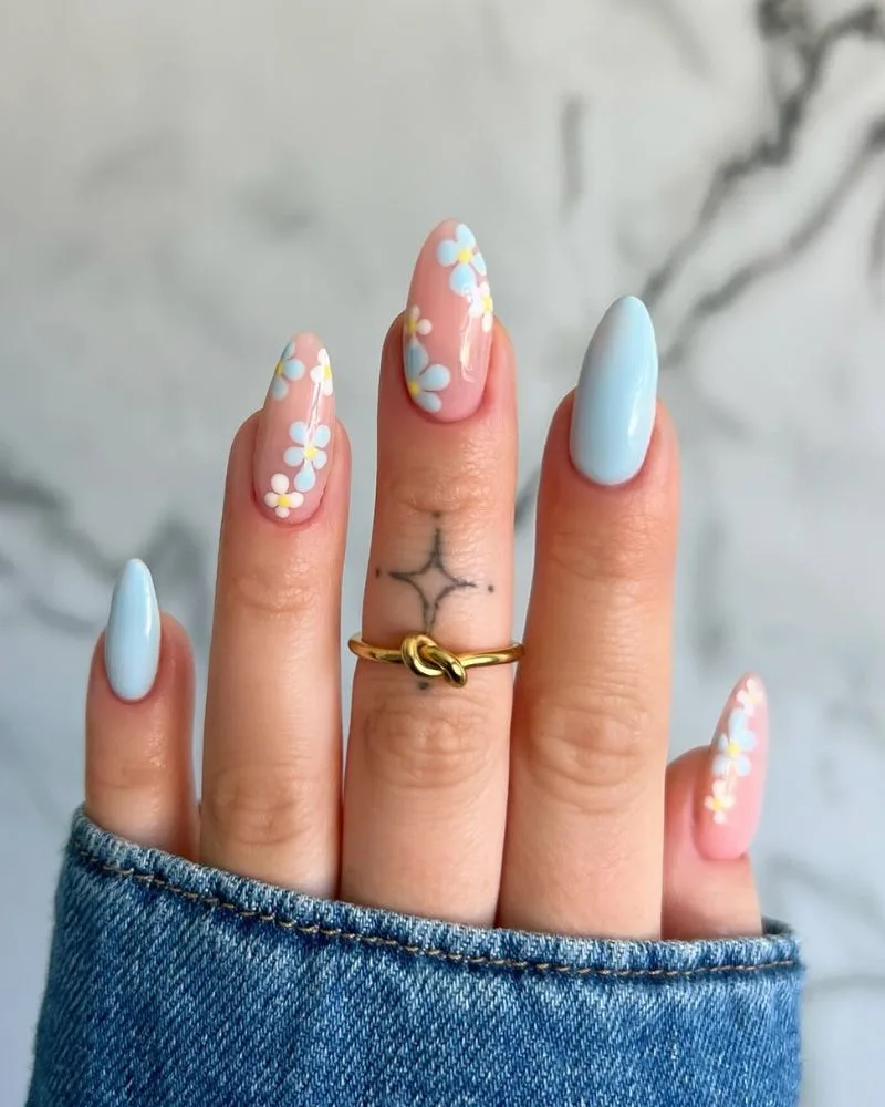 Ongles amande bleu ciel avec petit nail art floral blanc, manucure d'été sereine