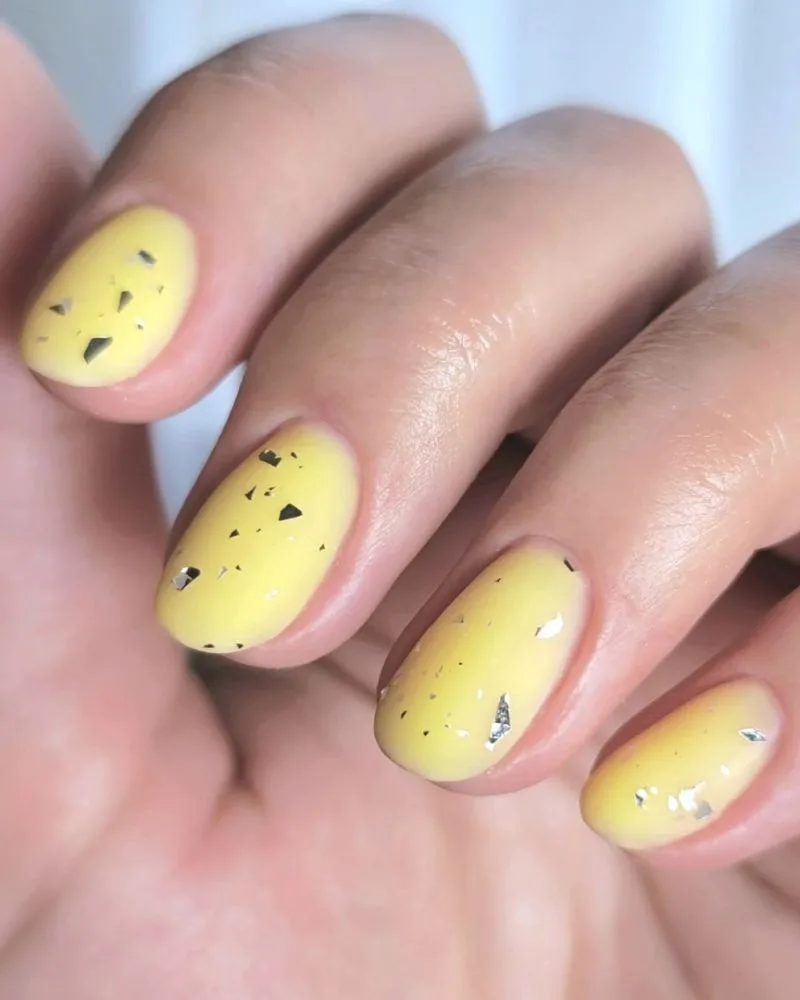 ongles courts jaune mat avec accents en feuille argentée pour l'été