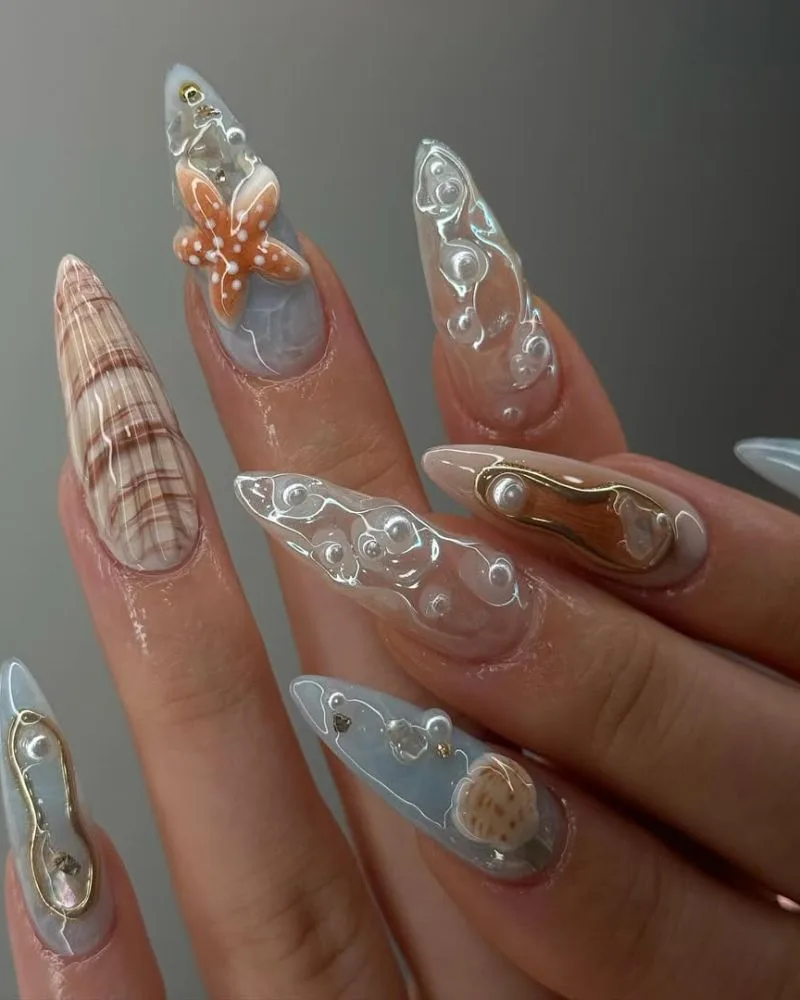 Ongles neutres avec nail art marbré, coquillage et détails argentés, manucure plage chic