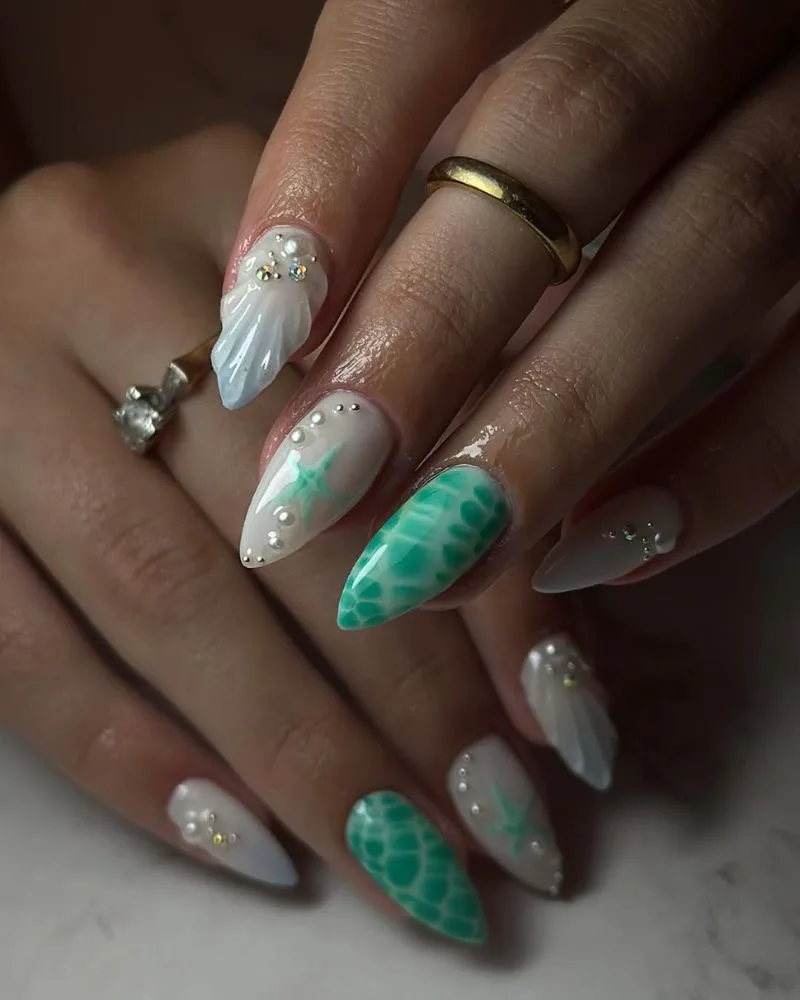 Ongles stiletto base laiteuse avec effet écaille de tortue verte et coquillages