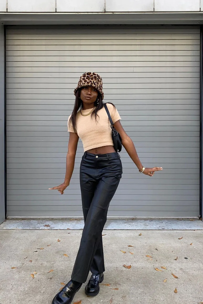 Pantalon en cuir porté avec un top beige et un bob