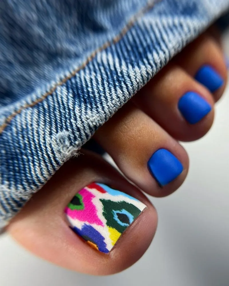 Pédicure bleu roi mat avec motif coloré sur le gros orteil, nail art d'été