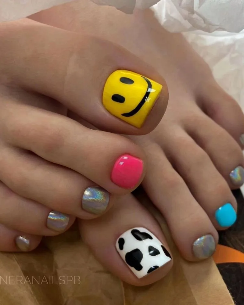 Pédicure fun avec smiley jaune et imprimé vache noir et blanc sur les orteils