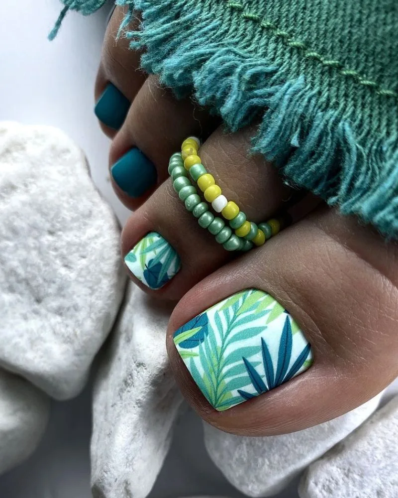 Pédicure motif jungle tropical avec feuillage vert et bleu sur les orteils