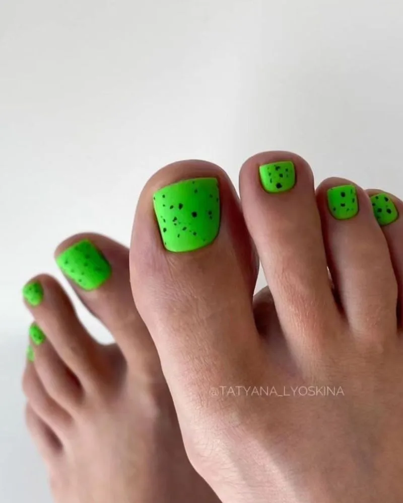 Pédicure vert vif éclatant avec petits pois noirs sur les orteils