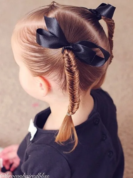 Petite fille avec deux couettes fishtail lisses et brillantes