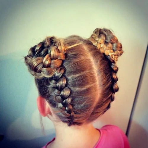 Petite fille avec deux tresses françaises inversées torsadées en chignons