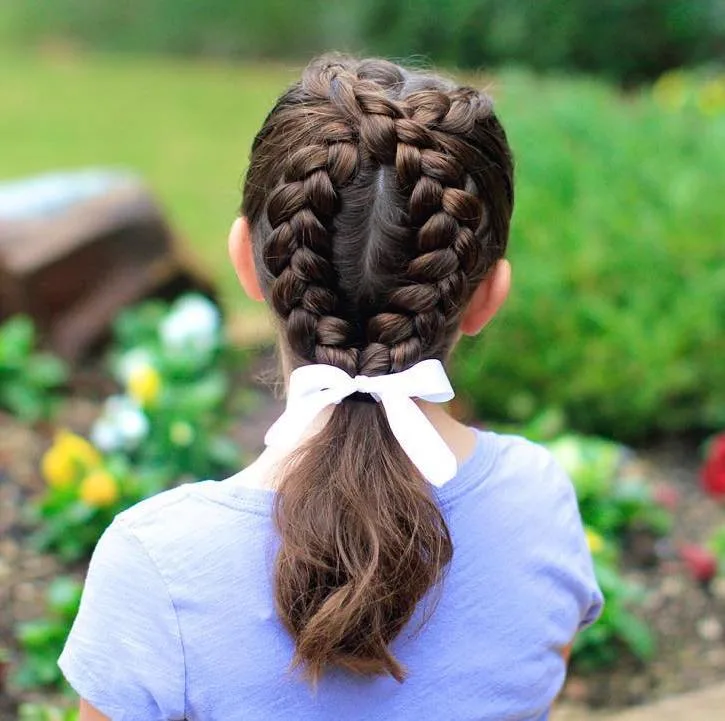 Petite fille avec dutch braid formant une boucle et queue basse, nœud blanc
