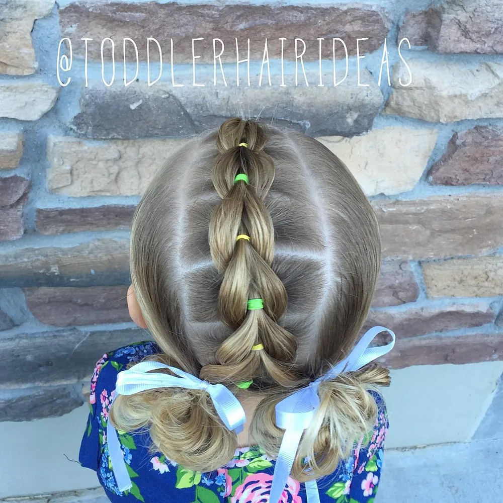 Petite fille avec mohawk pull-through, chignons désordonnés et rubans