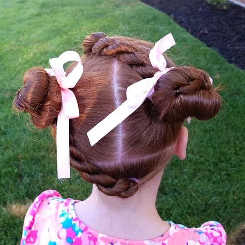 Petite fille avec space buns torsadés et nœuds, coiffure ludique