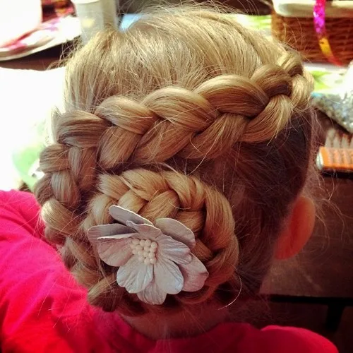 Petite fille avec tresse enroulée en chignon escargot et fleur, coiffure de fête