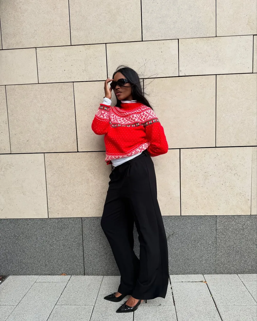 Pull jacquard rouge festif porté avec un pantalon large noir