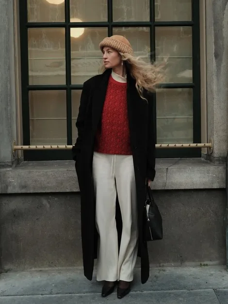 Pull texturé rouge et pantalon côtelé beige sous un long manteau