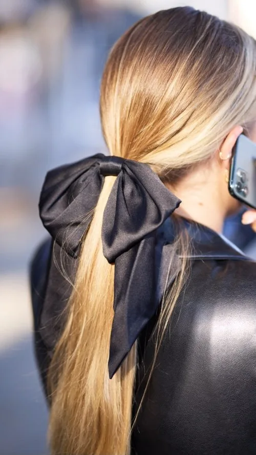 Queue de cheval basse ornée d'un gros nœud noir en satin, coiffure chic