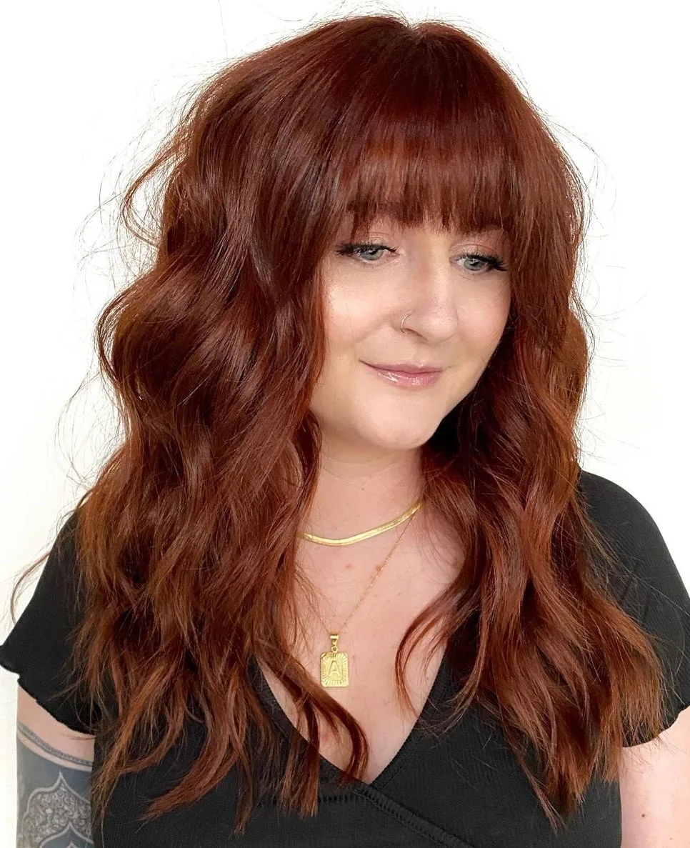 Shag auburn cuivré avec frange sur peau claire, cheveux mi-longs