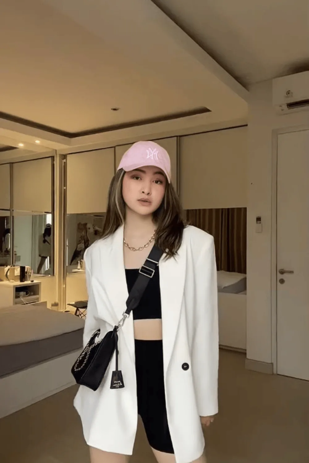 Blazer blanc porté sur une brassière noire et un short cycliste