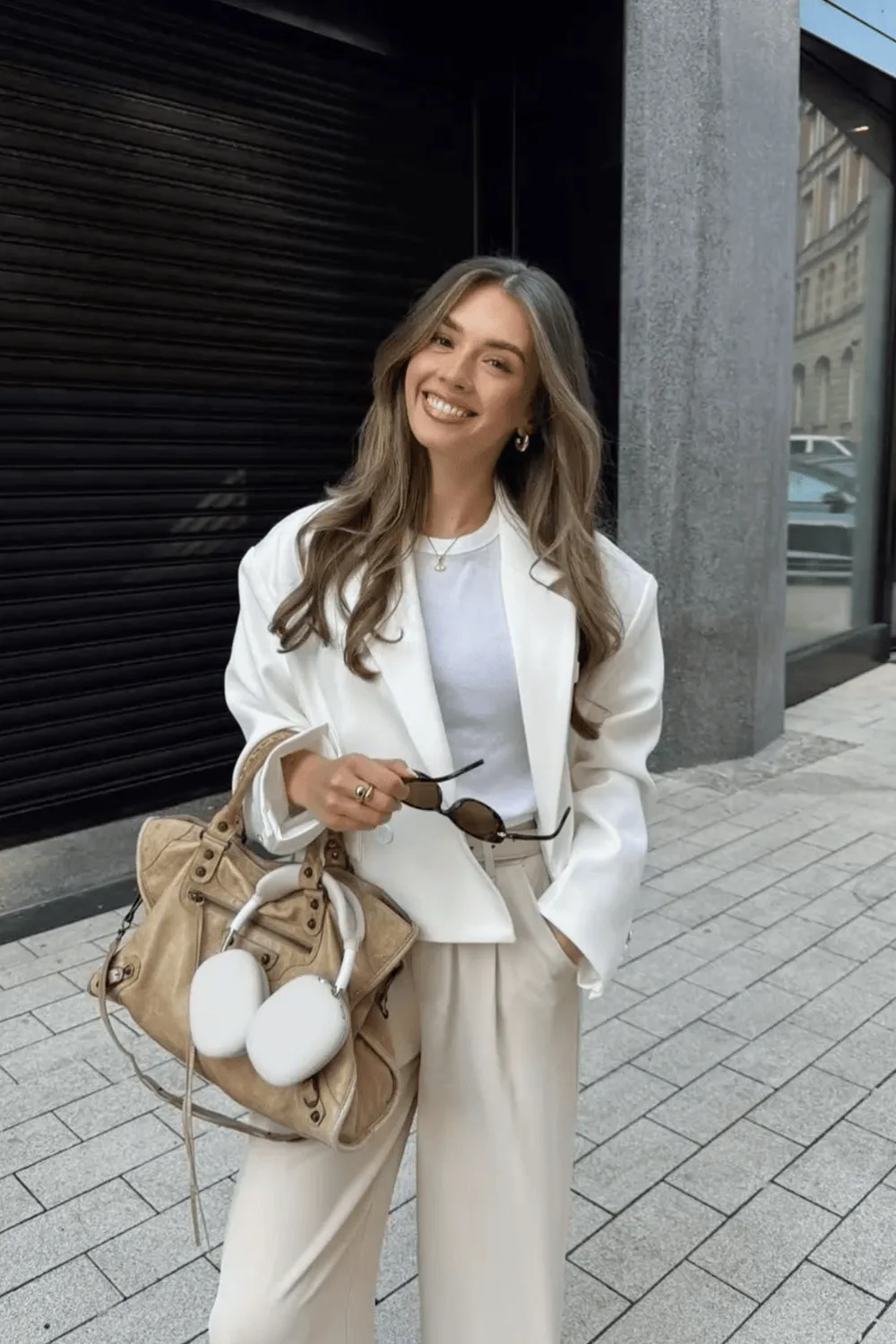 Blazer court blanc cassé porté sur un tee-shirt avec un pantalon beige fluide