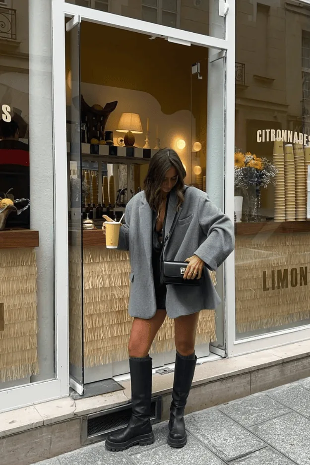 Blazer gris oversize porté avec des bottes hautes noires