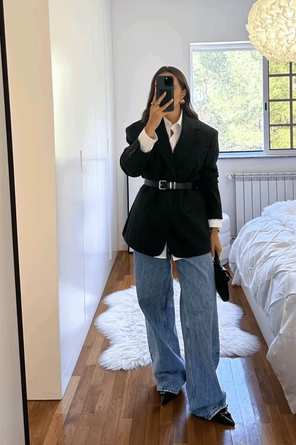 Blazer noir ceinturé à la taille porté sur une chemise blanche et un jean large