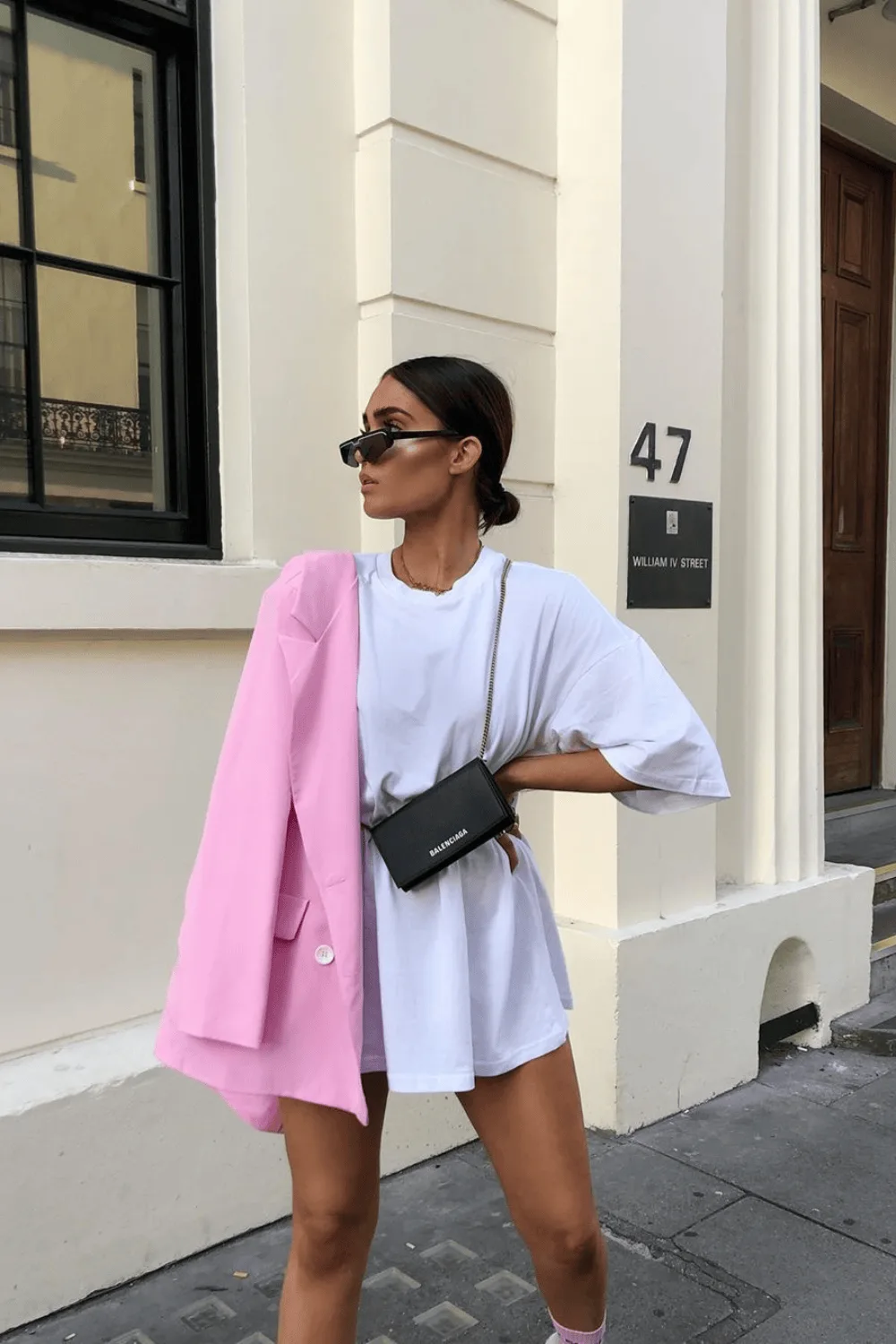 Blazer rose porté épaules sur une robe tee-shirt blanche oversize