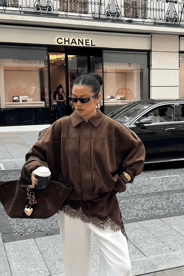 Bomber en cuir marron porté avec un top blanc et un pantalon crème