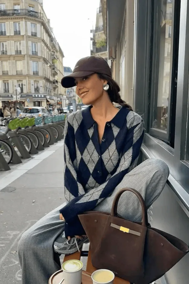 Cardigan bleu marine à losanges argyle porté avec un pantalon gris