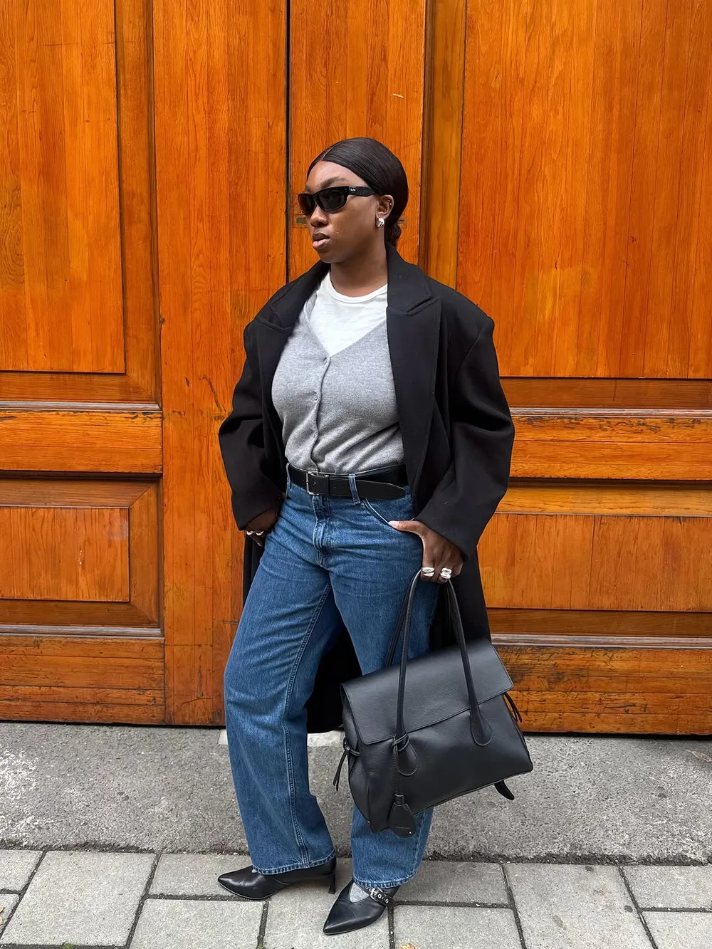 Cardigan gris porté sous un blazer noir avec jean bleu droit et sac noir