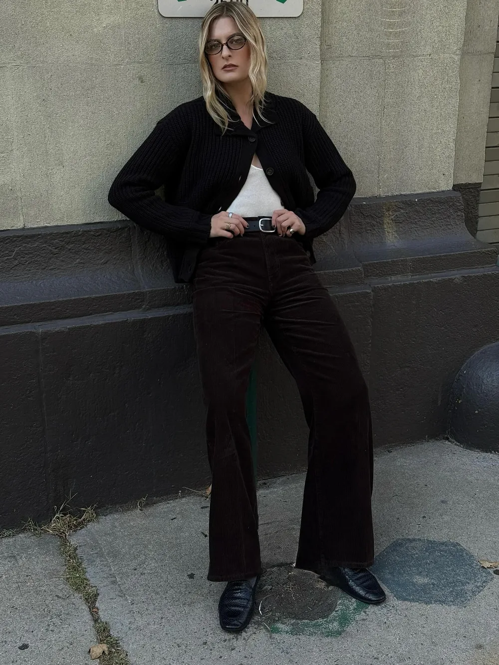 Cardigan noir porté avec un pantalon marron en velours côtelé et des mocassins