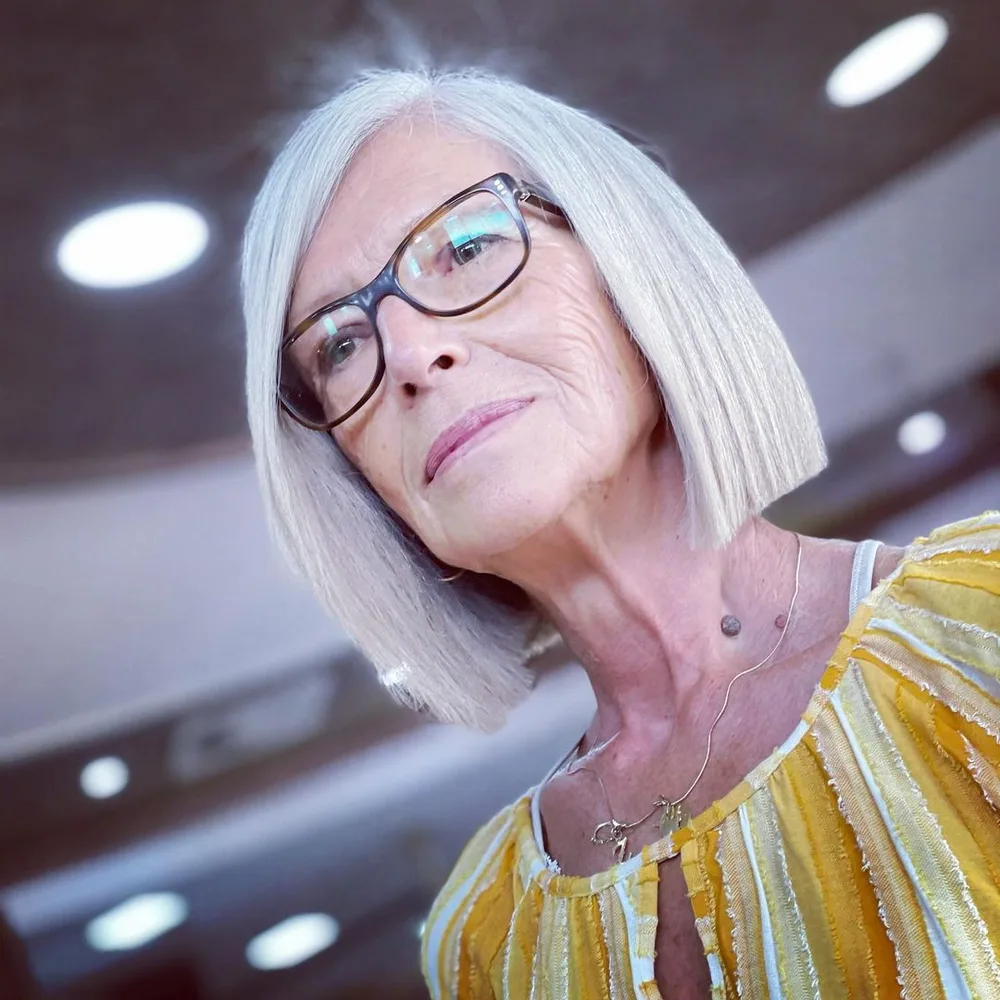 Carré droit gris argenté impeccable sur femme de 60 ans à lunettes