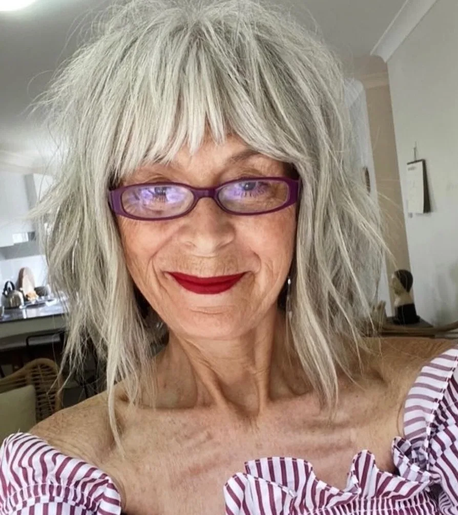 Carré shaggy gris à frange choppy et lunettes violettes sur femme mûre