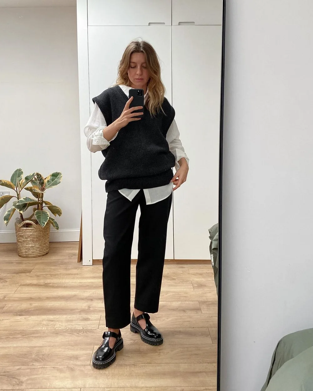Chemise blanche oversize portée sous un gilet noir et un pantalon noir