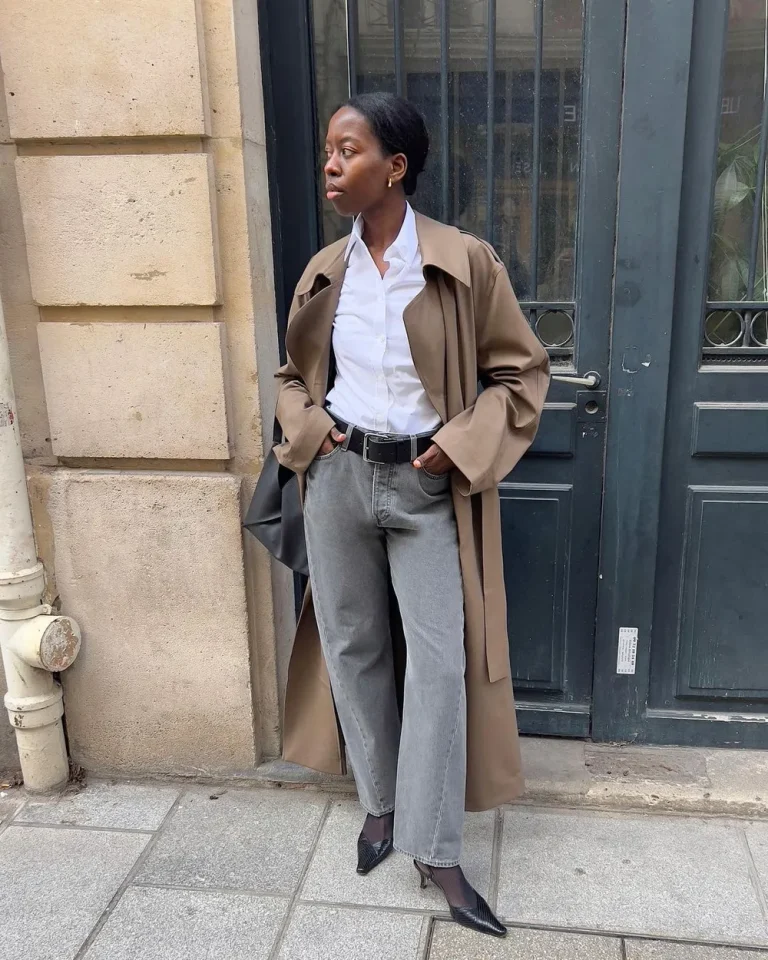 Chemise blanche rentrée dans un jean gris avec un trench
