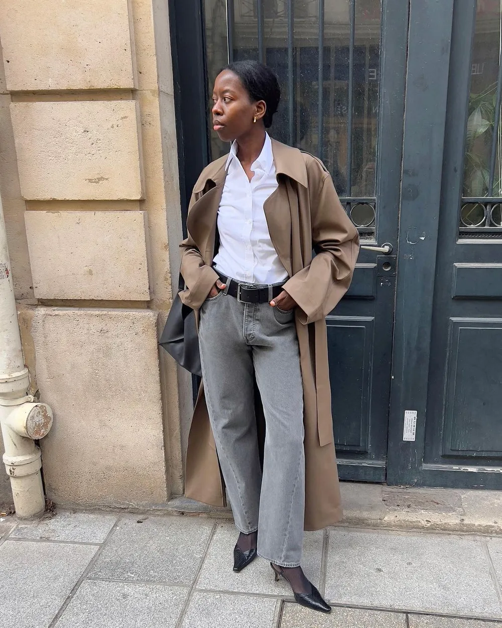Chemise blanche rentrée dans un jean gris avec un trench
