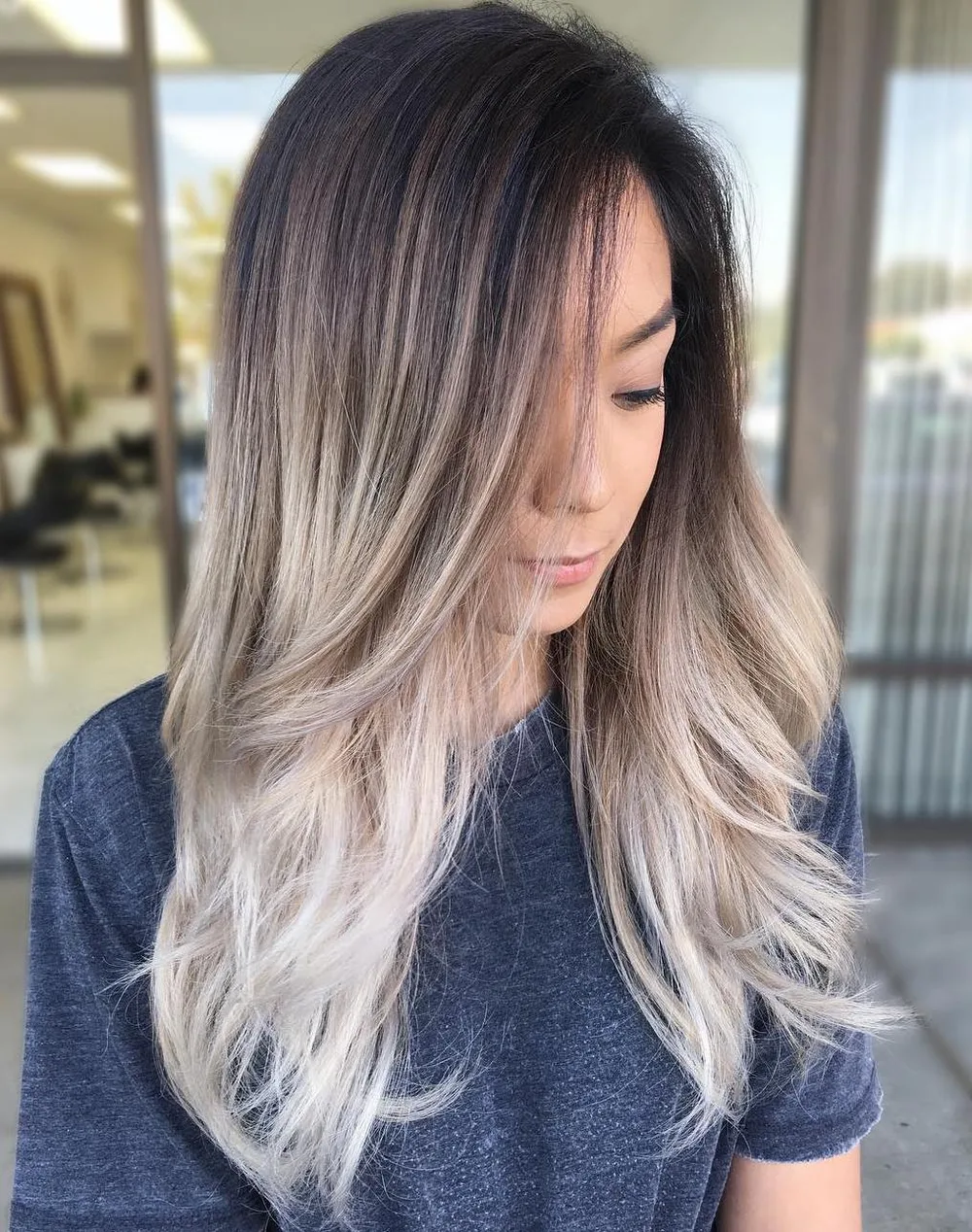 Cheveux avec racine foncée fondue vers des pointes blond glacé, de profil