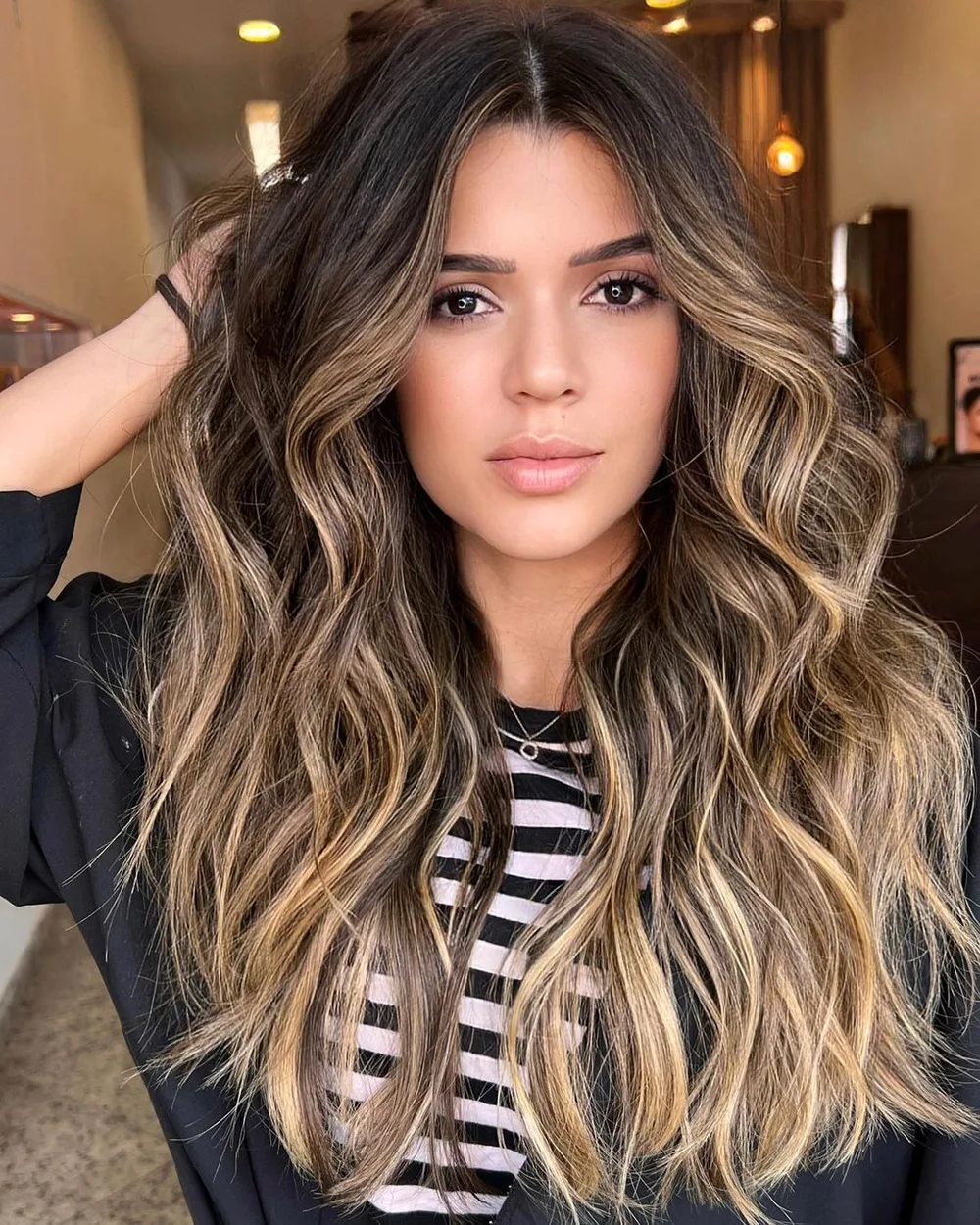 Cheveux bruns avec balayage miel caramel lumineux, longues ondulations, de face
