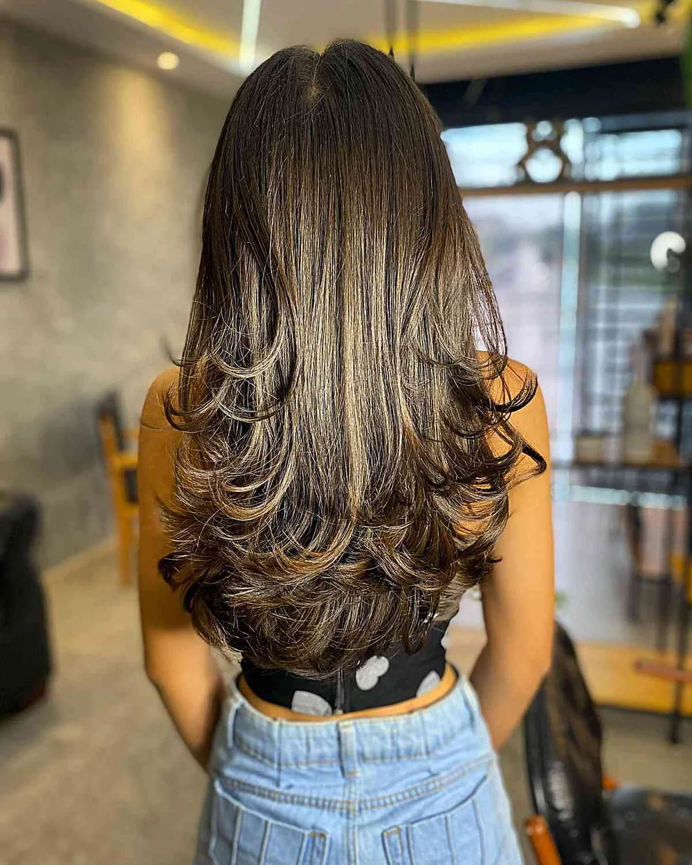 Cheveux chocolat aux reflets cannelle épicés, longueurs en couches ondulées