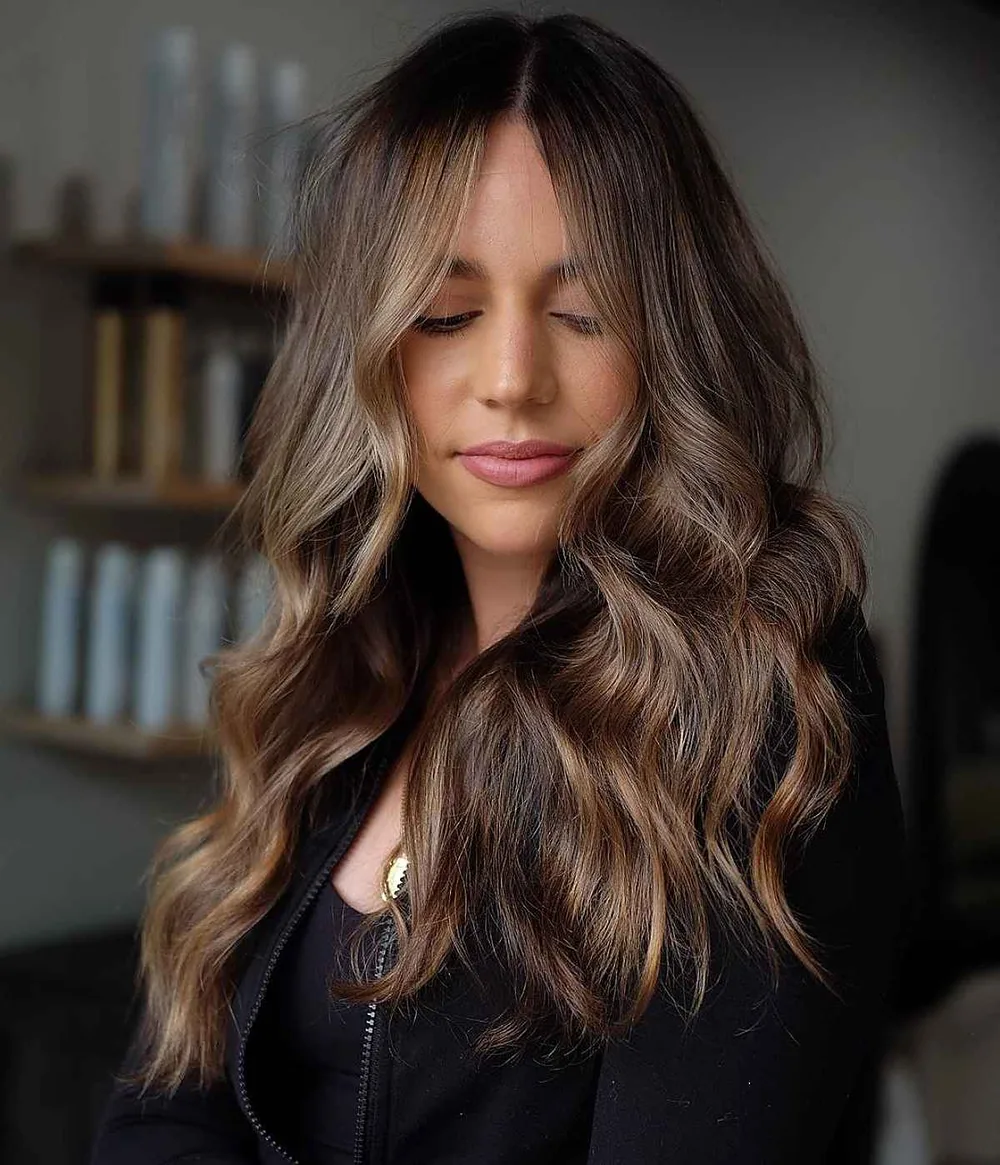 Cheveux chocolat en balayage fondu avec ondulations et frange, de face