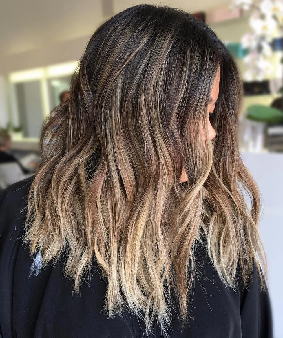 Cheveux chocolat foncé avec balayage subtil discret, longues ondulations, de profil