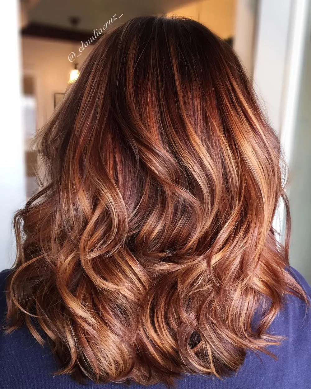 Cheveux cuivrés lumineux à reflets abricot, longueurs mi-longues ondulées