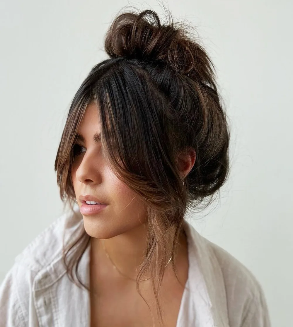 Chignon haut flou avec mèches libres autour du visage