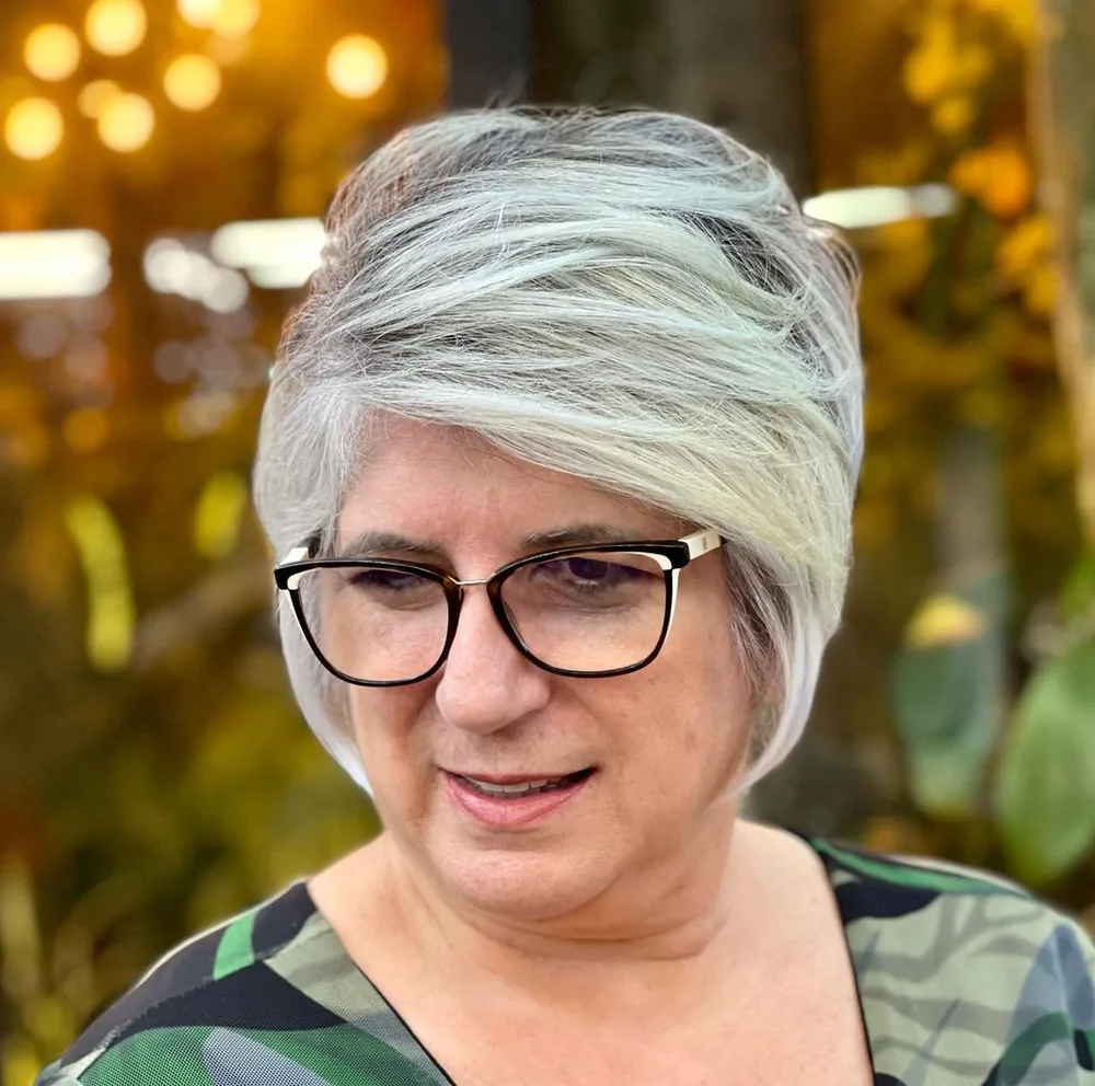 Coupe bixie argentée à raie profonde sur femme de 60 ans à lunettes