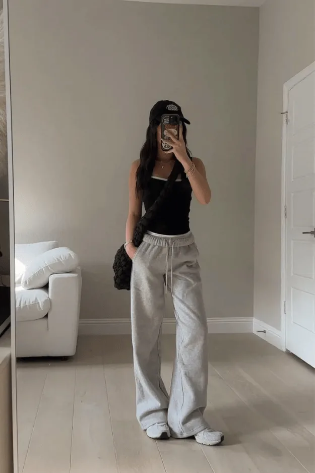 Débardeur noir porté avec un jogging gris, une casquette et un sac noir