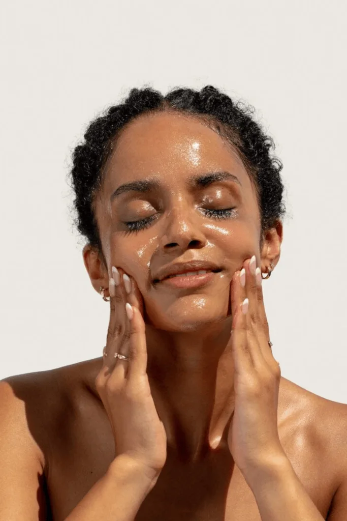 Femme au teint glowy appliquant son soin, peau lumineuse et saine