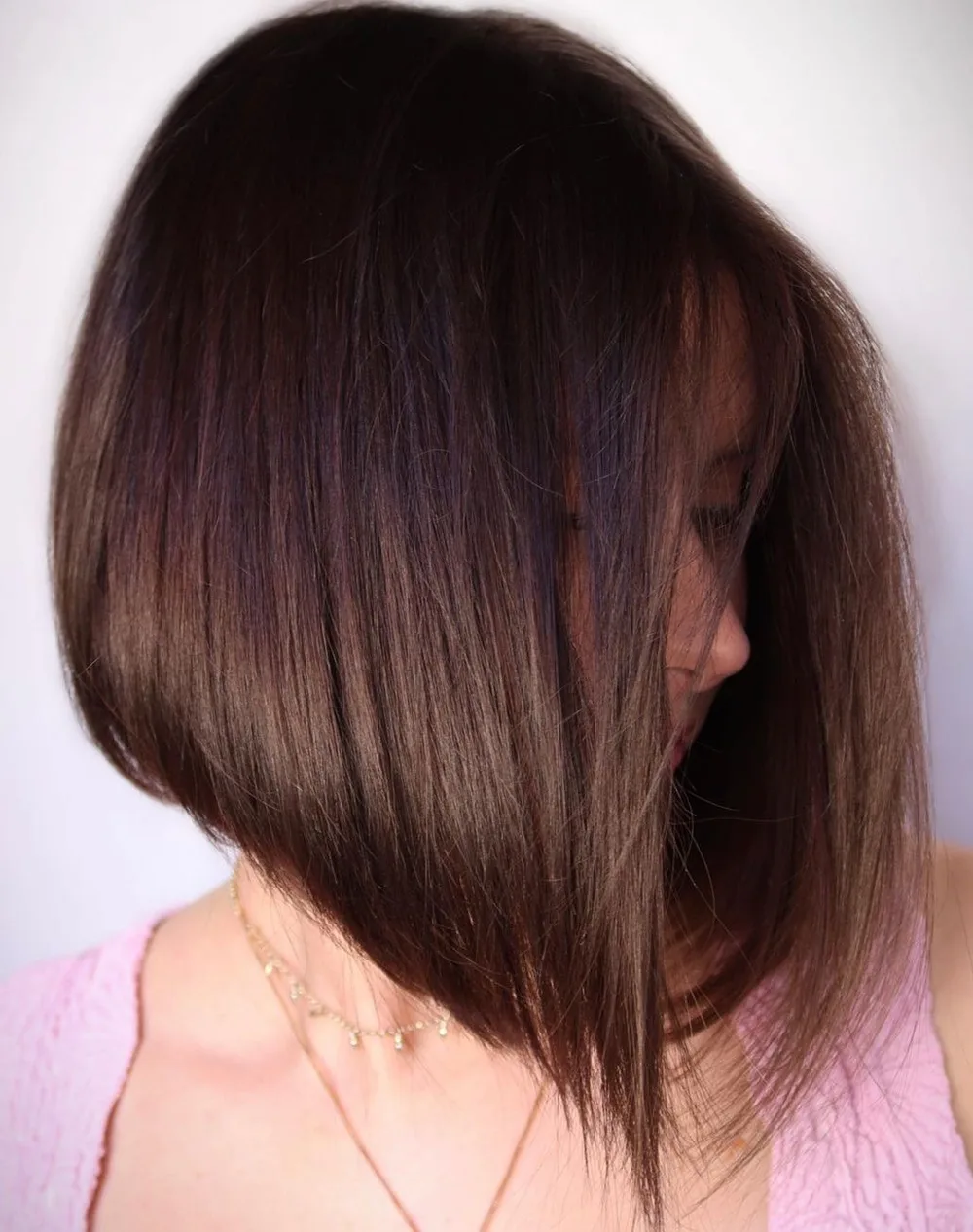 Femme aux cheveux lisses avec un carré plongeant brun brillant, de profil