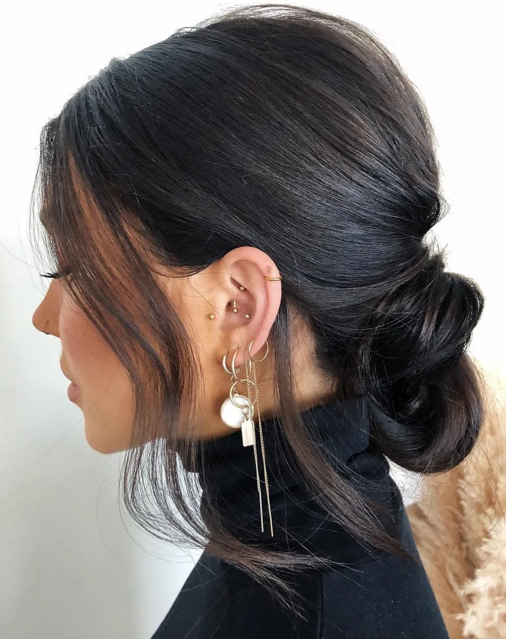 Femme aux cheveux lisses coiffée en chignon bas flou et légèrement décoiffé, de profil