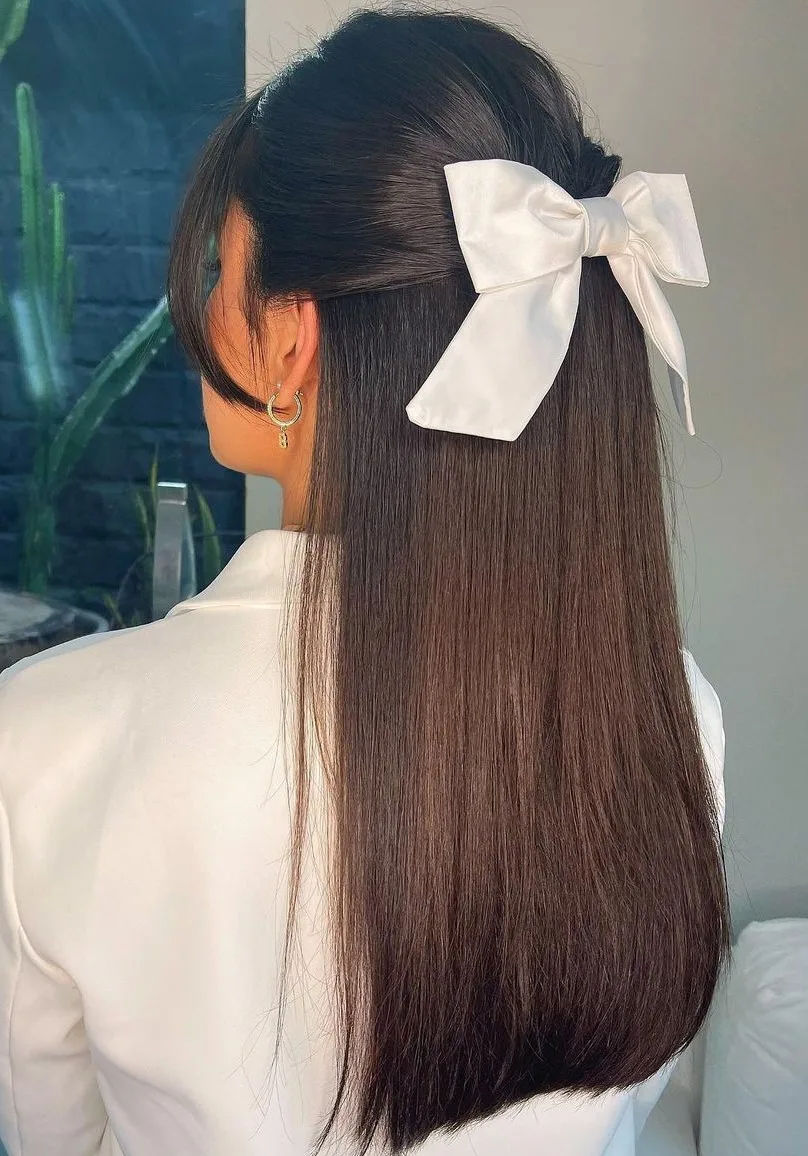 Femme aux cheveux lisses coiffée en queue de cheval haute avec un noeud, de face